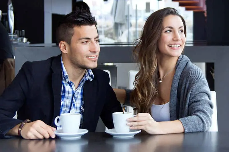 smiling man and woman at cafe looking away