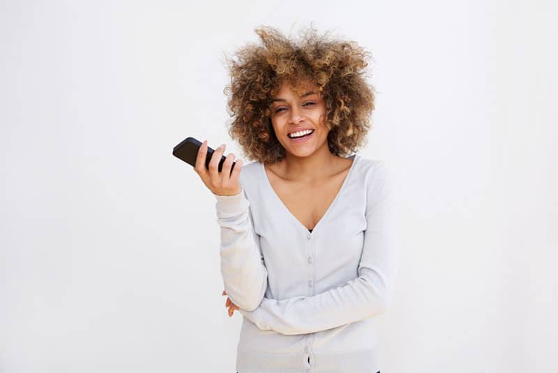 Mulher sorridente a posar com um telemóvel