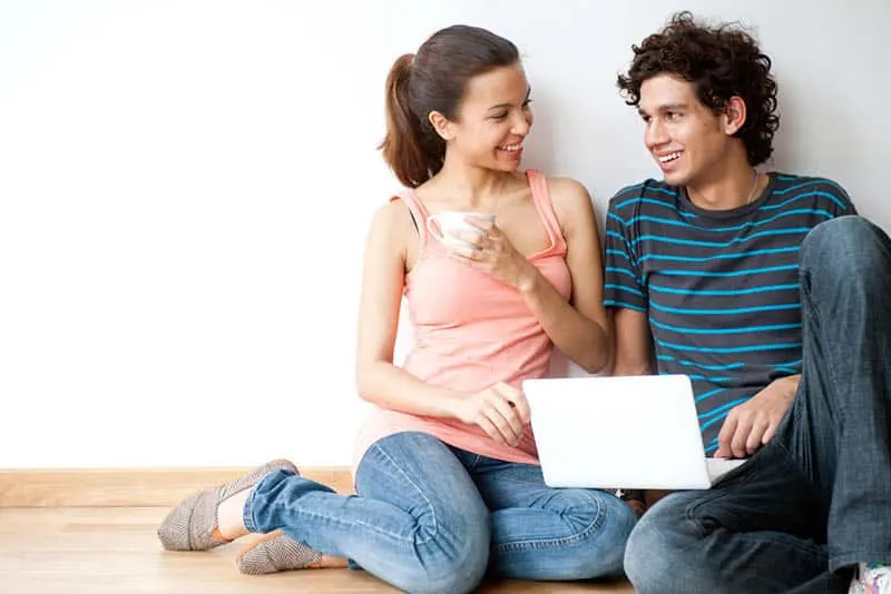 smiling young couple looking each other while sitting on floor
