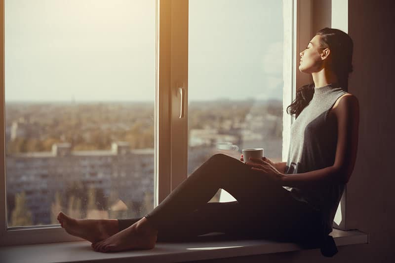 Frau, die Kaffee am Fenster trinkt