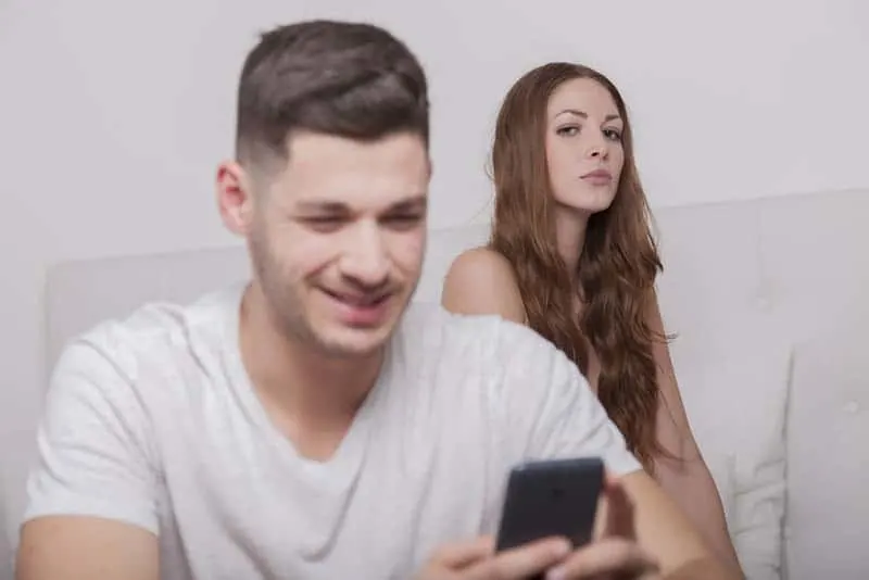 woman looking at man typing on phone