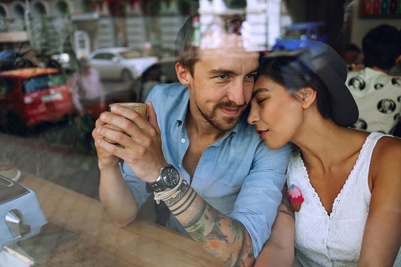 woman lying on man shoulder at cafe