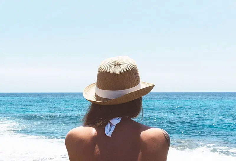 woman with hat looking at sea