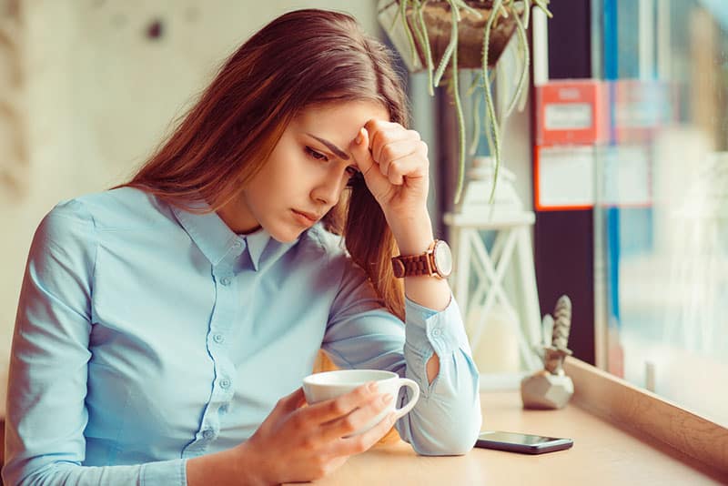 donna preoccupata seduta in un caffè