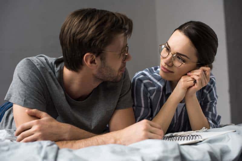 young couple lying in bed and looking at each other