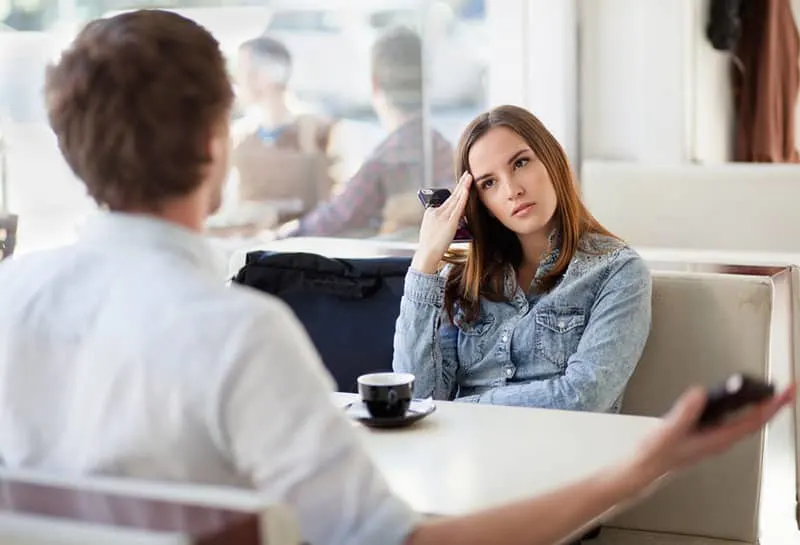 young mindful woman looking at man at cafe