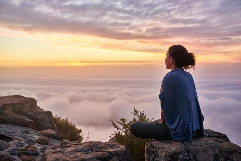  jeune femme assise paisiblement sur la montagne 