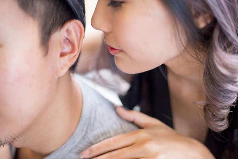 young woman whispering on man ear