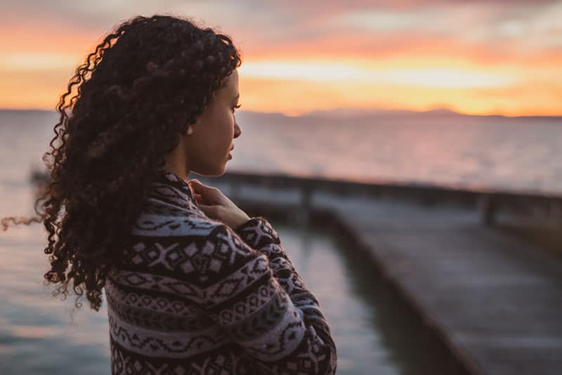 mujer joven con el pelo rizado de pie junto al mar