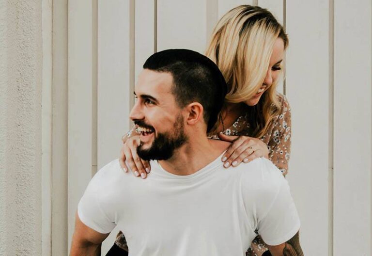 smiling man piggybacking his girlfriend
