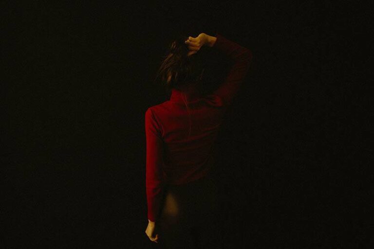 back view of woman wearing red dress with black background