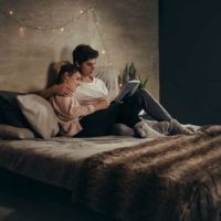 couple lying on bed and reading a book