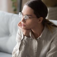 mujer preocupada con gafas sentada en el salón