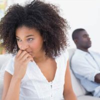 upset woman sitting beside man at home