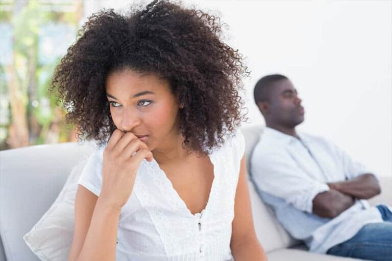 upset woman sitting beside man at home