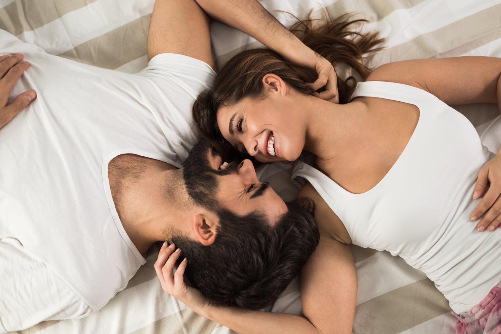 a happy couple hugging on the bed