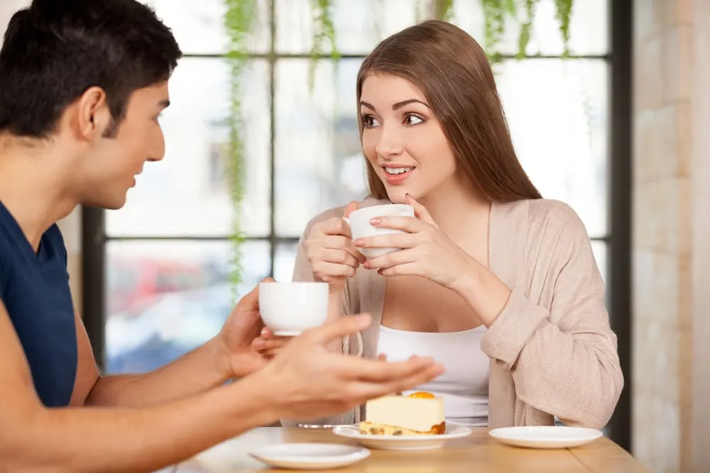 a man and a woman talking while drinking coffee