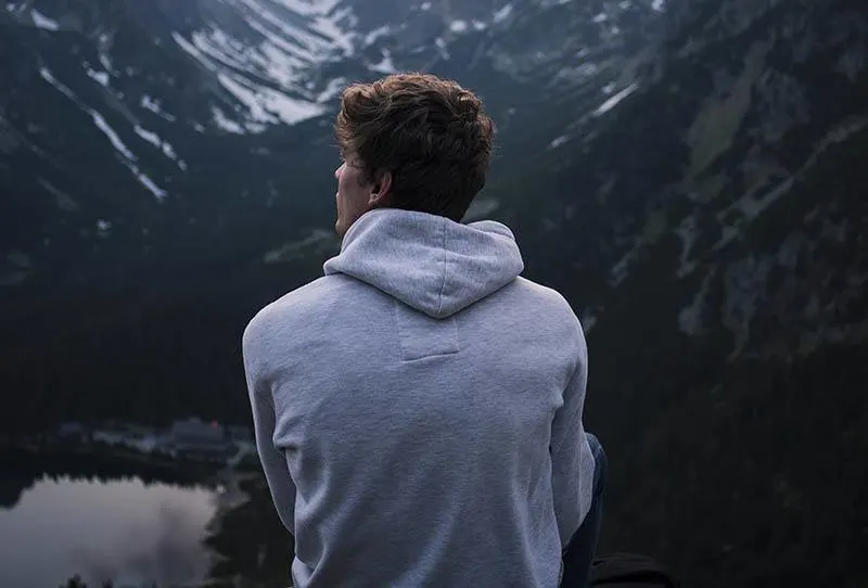 back view of man sitting on top of mountain