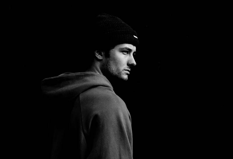 black and white photo of man wearing hat and hoodie