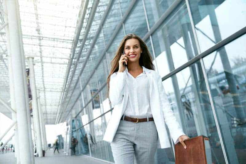 business woman holding suitcase and talking on her phone