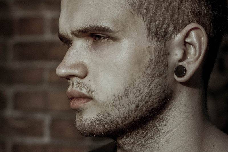close up photo of side view thoughtful man wearing earring