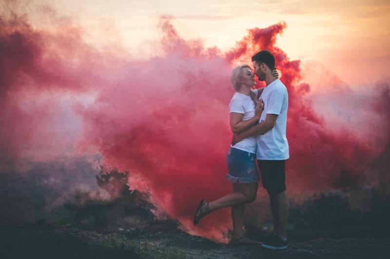 casal abraçado ao lado de fumo cor-de-rosa