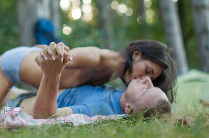 couple lying down in nature and kissing