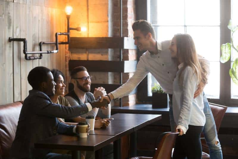 friends meeting in cafe, young man introducing