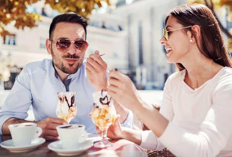 uomo e donna felici che mangiano un gelato al bar
