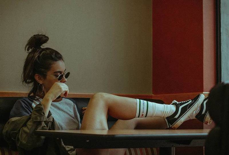 donna hipster mette le gambe sul tavolo in un caffè