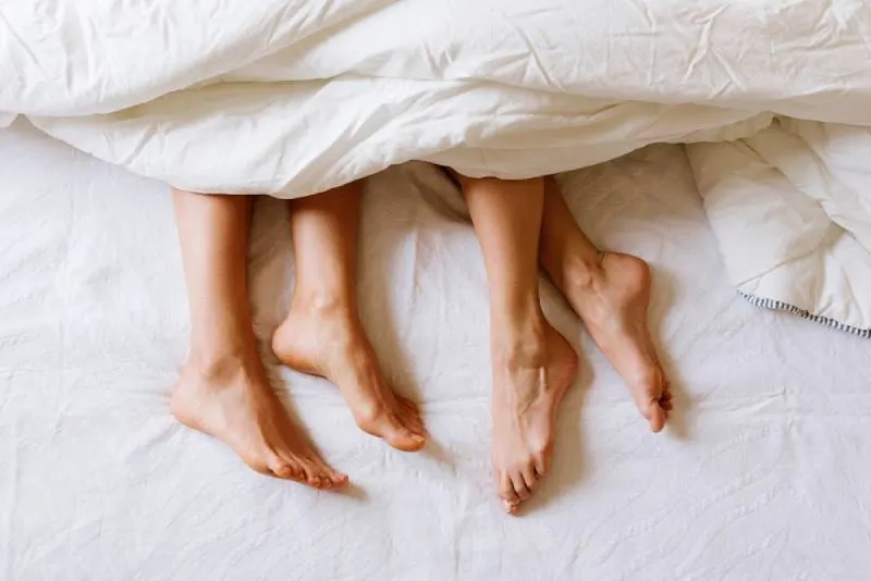 male and female feet under the sheets