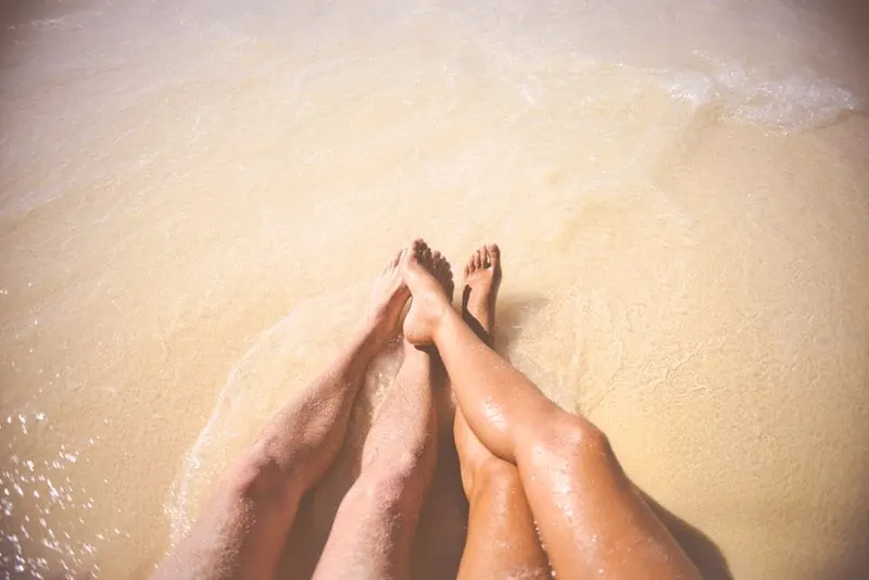 man and woman legs at the beach