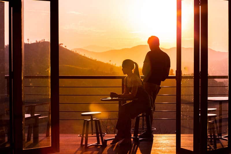 uomo e donna sul balcone di un caffè durante il tramonto