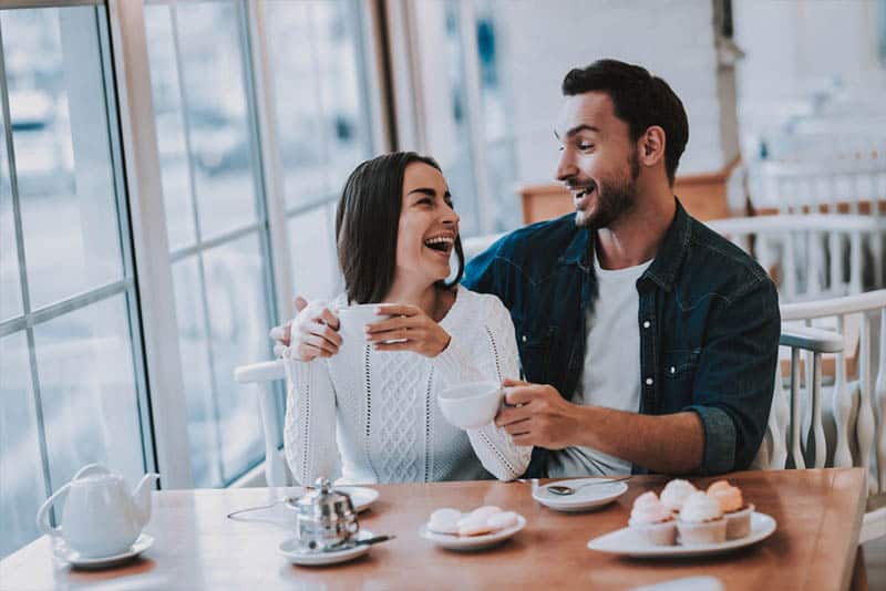 homem e mulher sentados num restaurante a sorrir e a olhar um para o outro