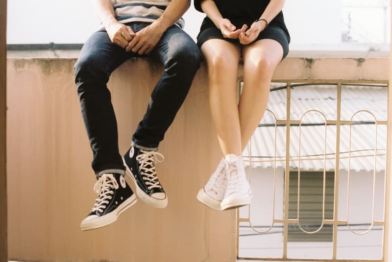 man and woman wearing converse all star sitting on balcony