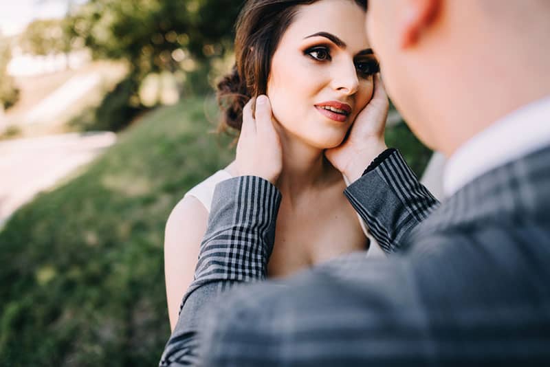 hombre lleva las manos a la cara de la mujer