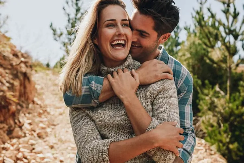 man hugging smiling woman from back
