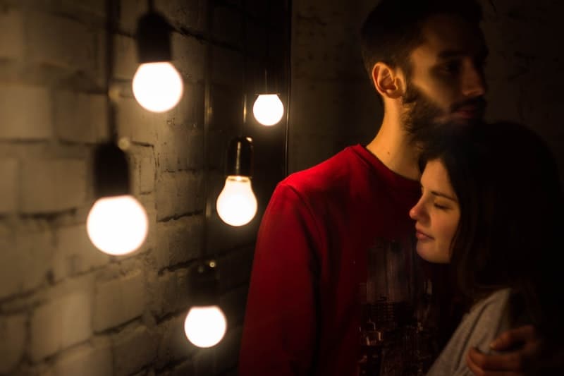 man hugging woman beside light bulbs