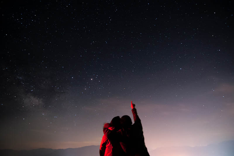 hombre señalando las estrellas mientras abraza a una mujer