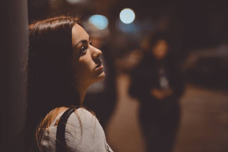 portret van nadenkende vrouw leunend tegen straat