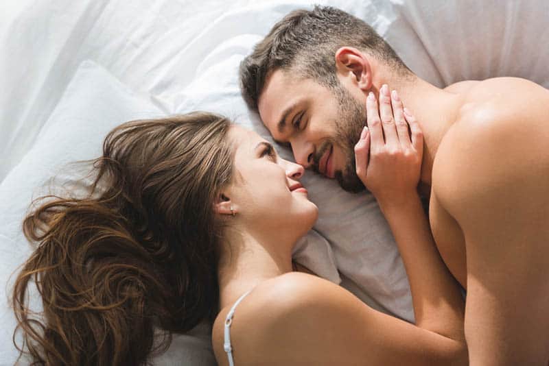 romantic couple looking each other and lying on bed