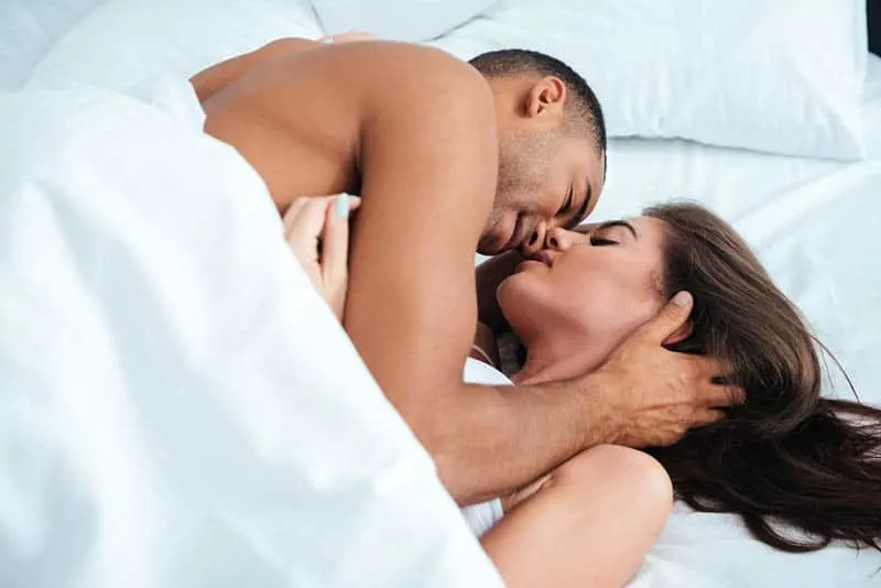 romantic couple lying on bed under blanket