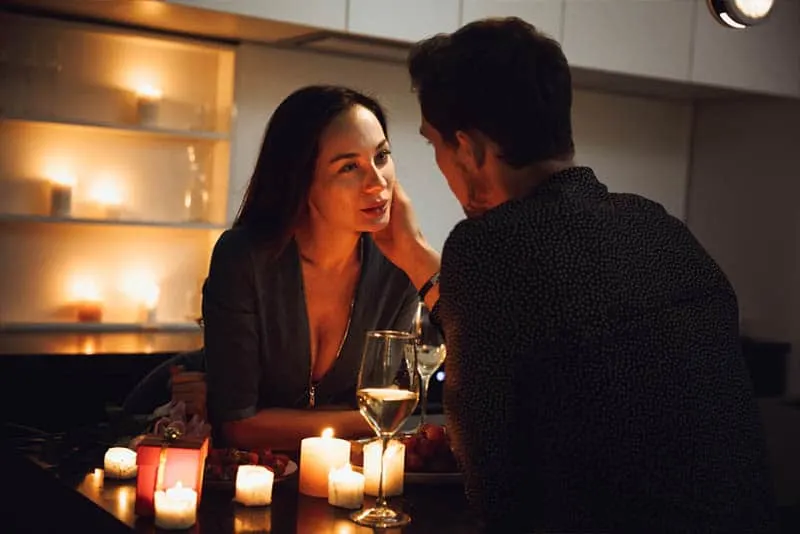 romantic couple sitting on table with candles