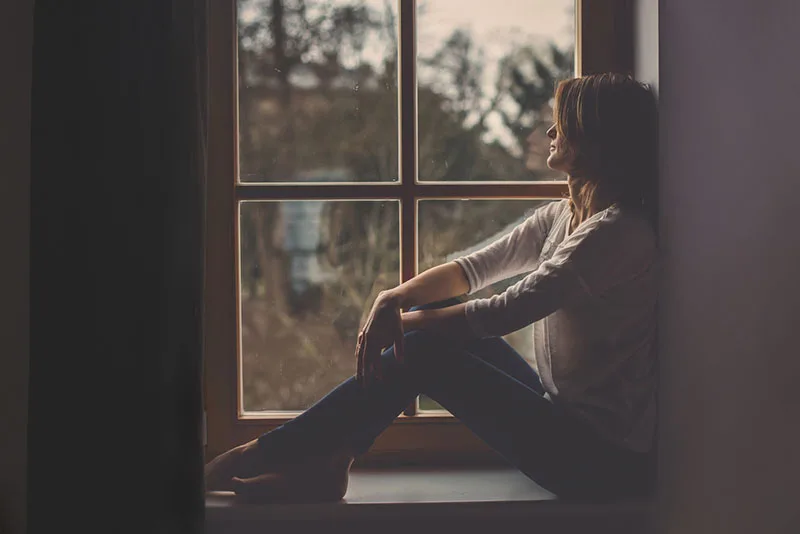 sad woman sitting by the window