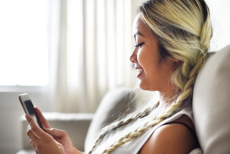 vista laterale di una donna sorridente che scrive al cellulare