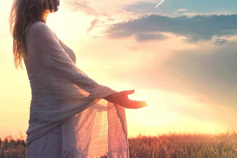 side view of woman standing in field during sunset