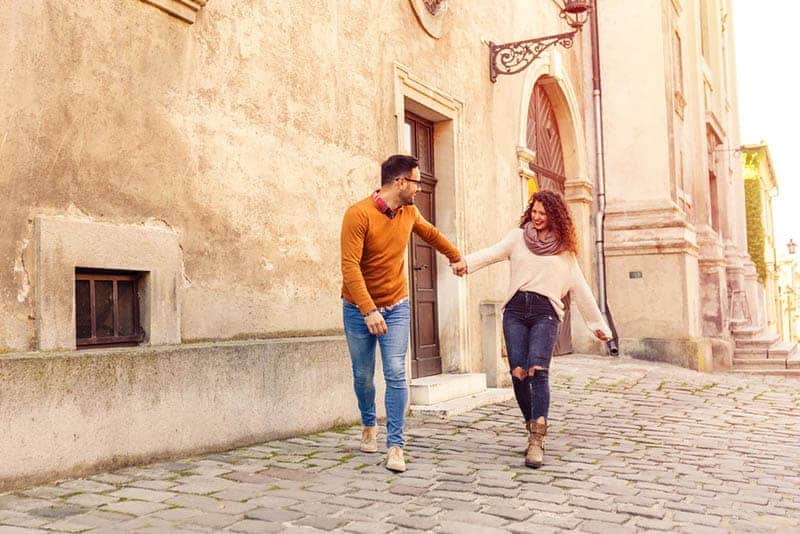 smiling couple holding hands on the street