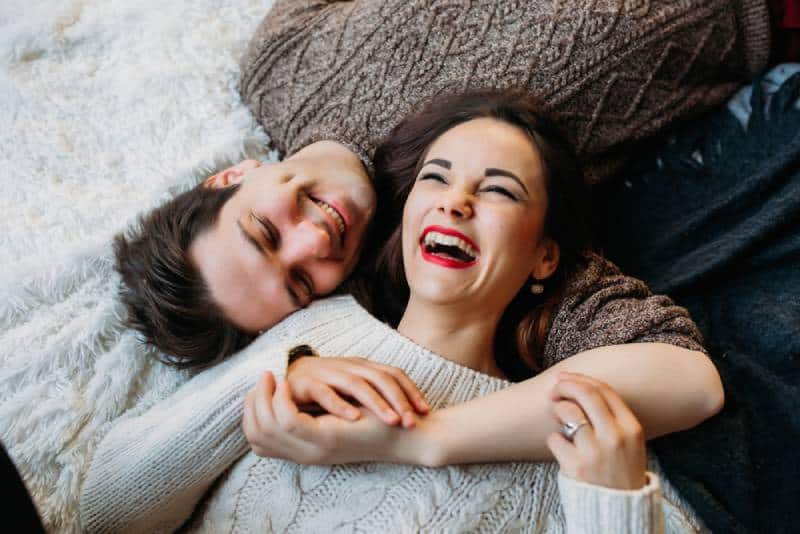 pareja sonriente tumbada en el suelo