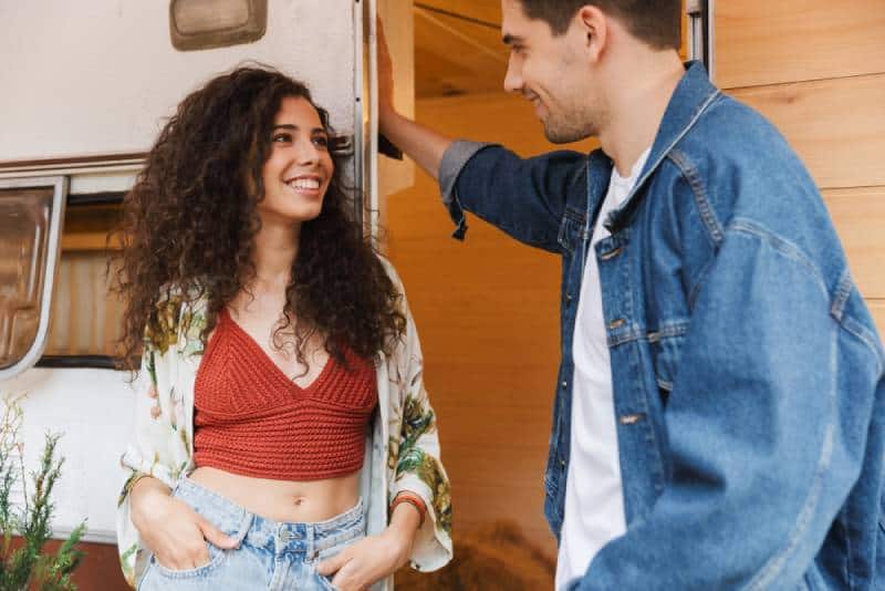 smiling couple talking while standing near house