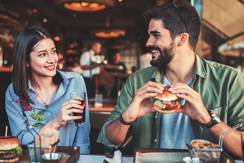 Pareja joven y sonriente que se mira en un restaurante